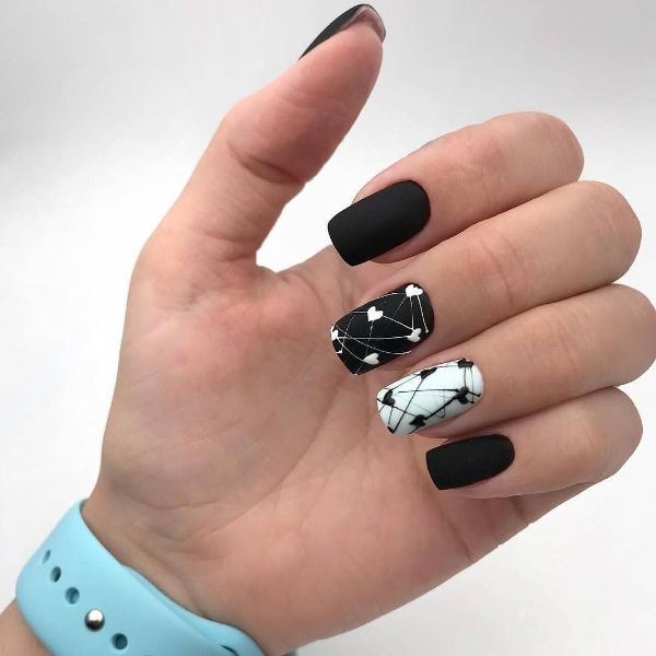 black nails with hearts and white accent nail